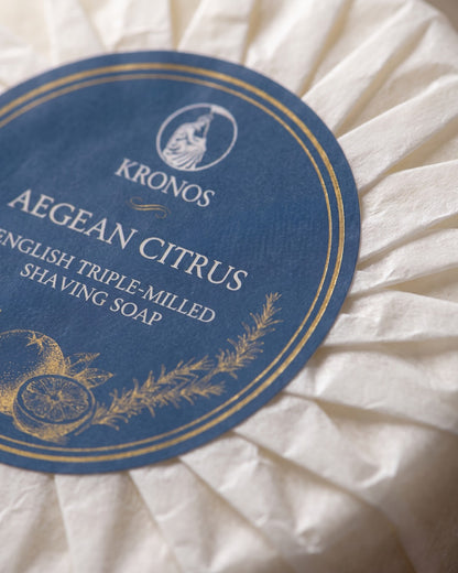 Close-up of the Kronos Aegean Citrus label: English triple-milled shaving soap, with gold drawings of citrus and rosemary on navy