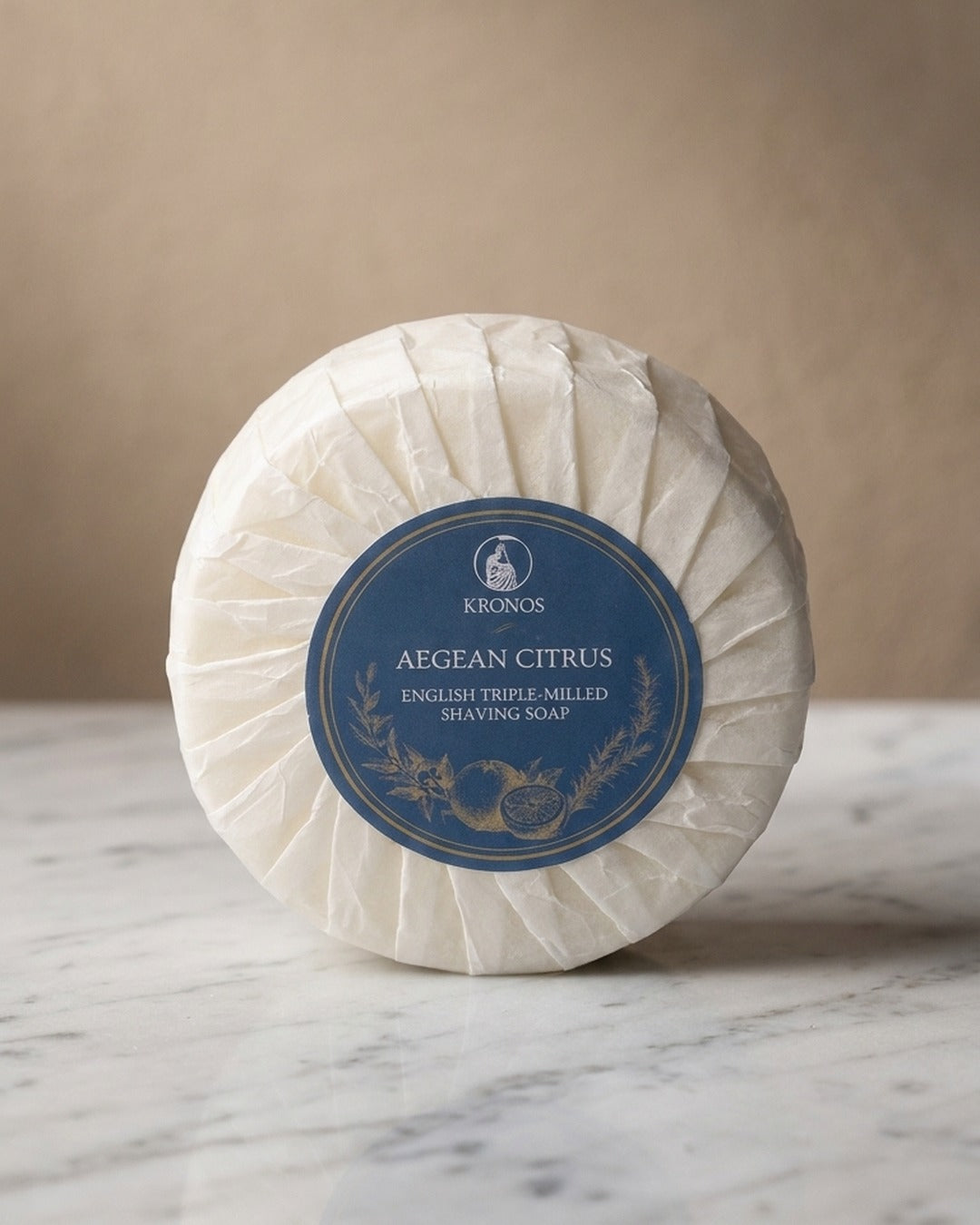 Kronos Aegean Citrus shaving soap standing on white marble against a warm beige wall