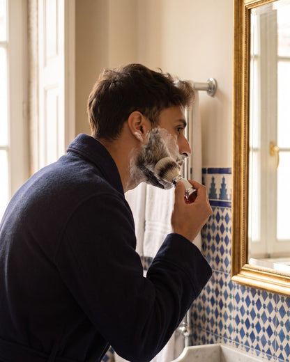 A man raising shaving lather with the Kronos shaving brush at a traditional bathroom basin