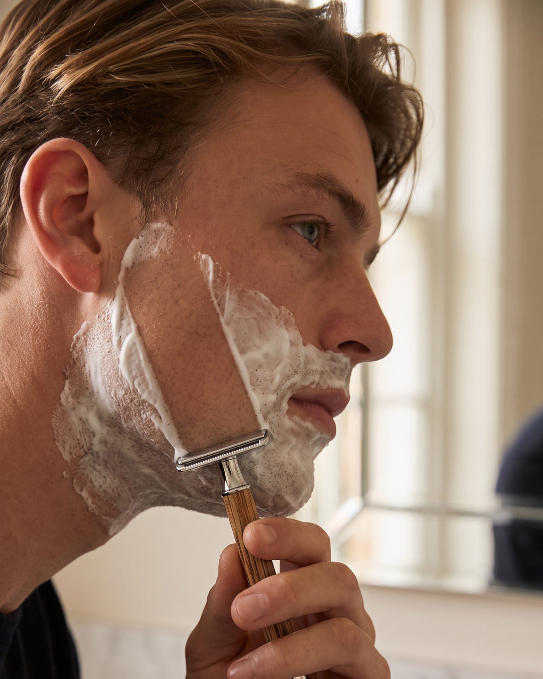 Close-up of a man shaving with the bamboo razor from the Kronos Home Barber Set