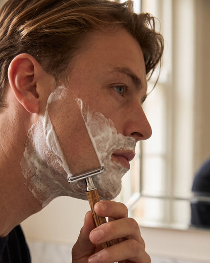 Close-up of a man shaving with the bamboo razor from the Kronos Home Barber Set