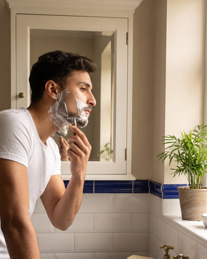 A man shaving with the Kronos bamboo safety razor in a heritage bathroom
