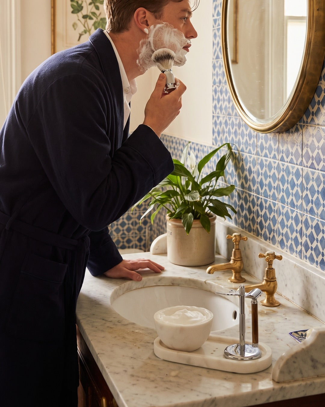 A man shaving at the basin with the Kronos marble bowl and tray on the washstand
