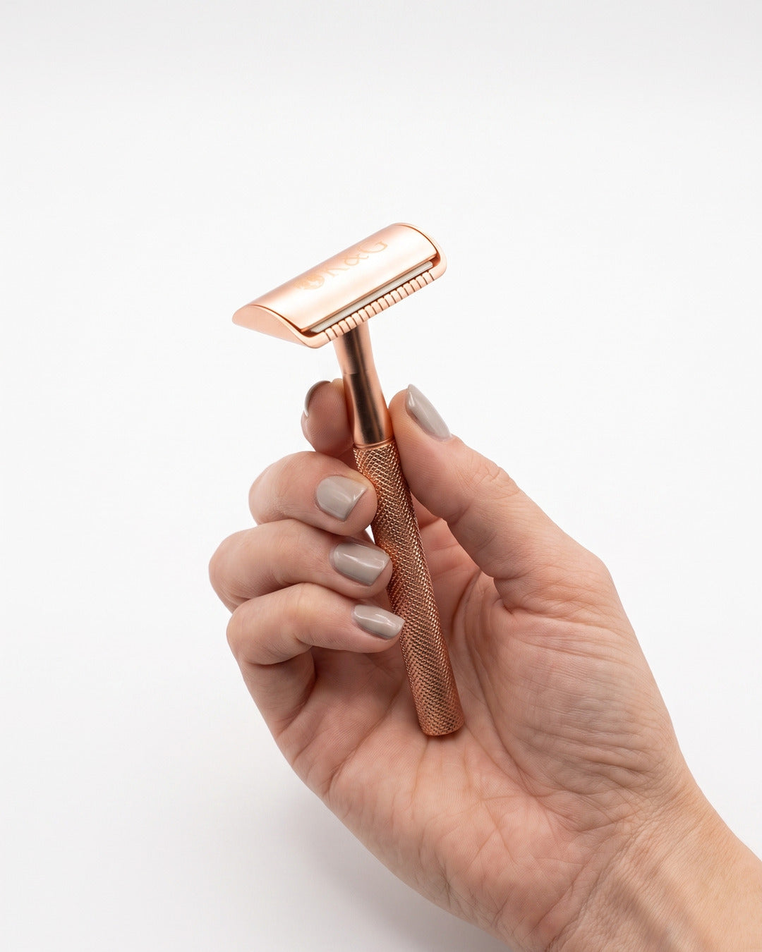 Rose gold safety razor held in a hand, showing its size