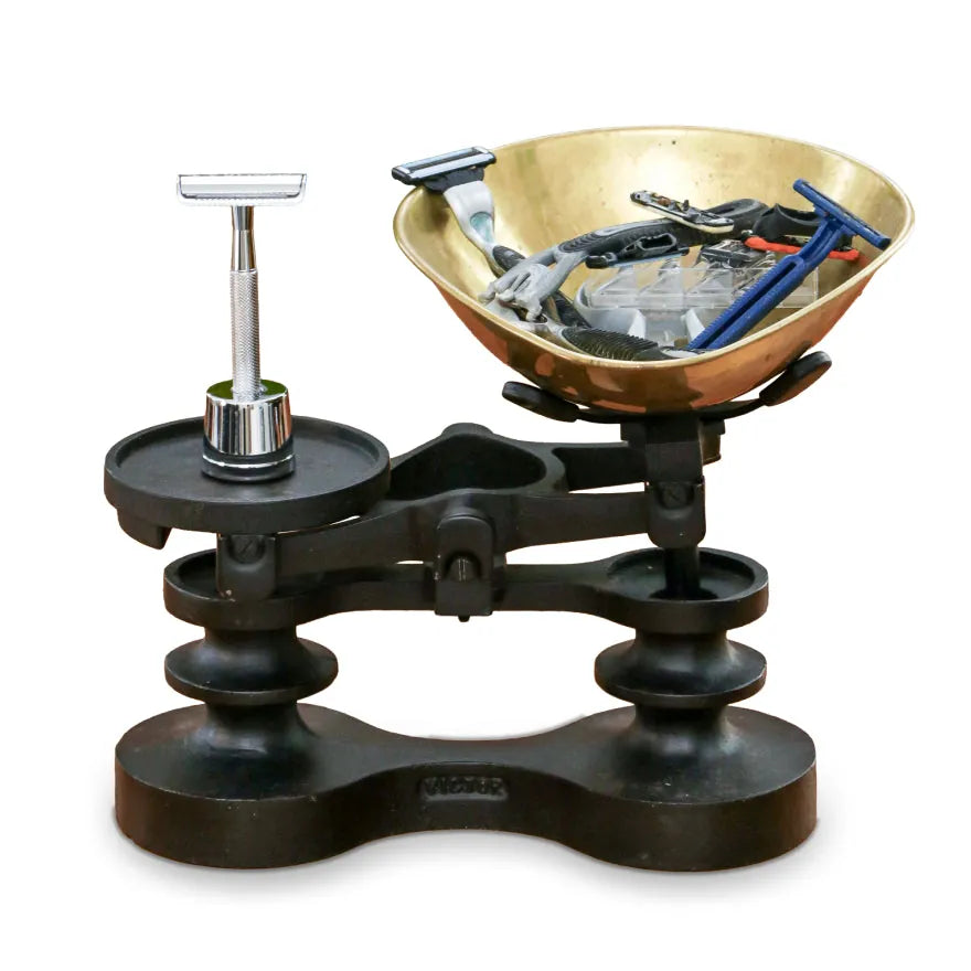 The safety razor on one side of antique scales, a bowl of cartridges on the other